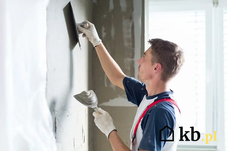 Tynkowanie ścian - robotnik tynkuje ściany podczas prac wykończeniowych w domu w stanie surowym zamkniętym.
