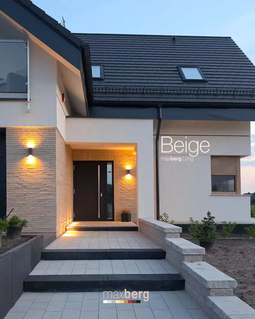 Długie beżowe płytki elewacyjne Maxberg Long Beige przy wejściu do domu, podświetlone ciepłym światłem kinkietów