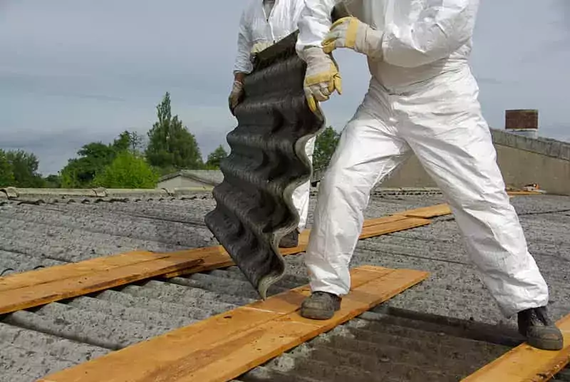 Robotnicy usuwający azbest z dachu