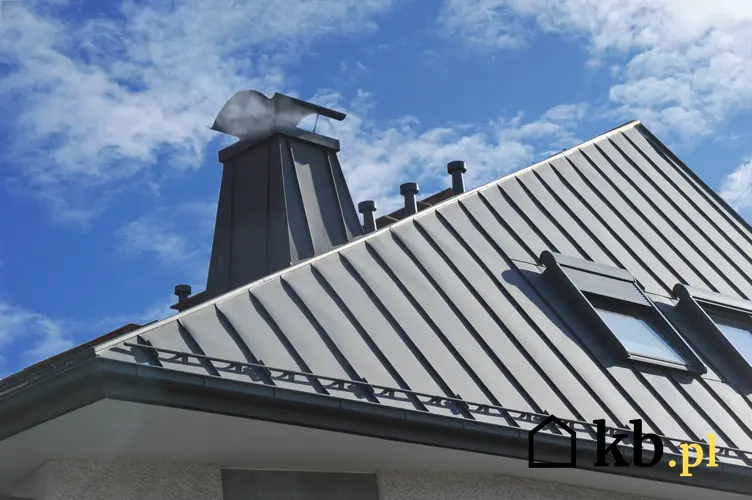 Dach z kominem na tle nieba, a także ława kominiarska, ławeczka na dachu