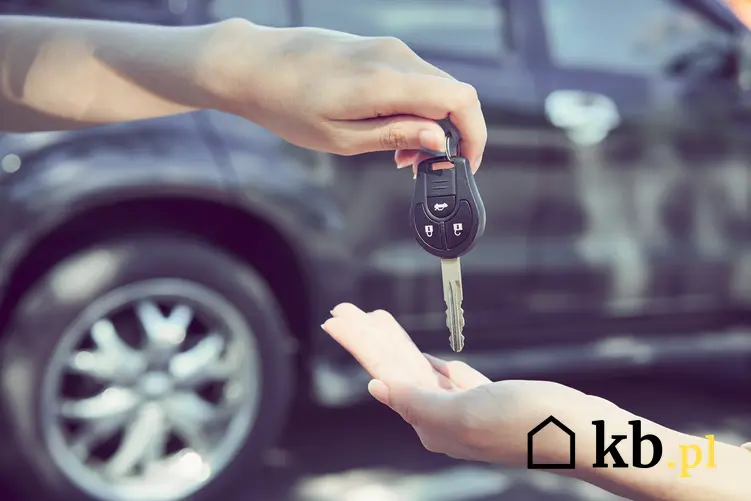 Dłonie przekazujące kluczyki do auta, a także umowa kupna sprzedaży samochodu a dwóch właścicieli