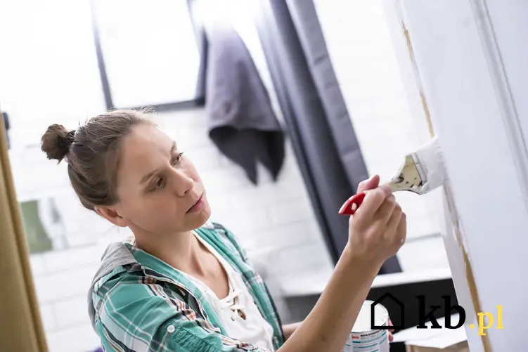 Kobieta malująca pędzelkiem detale w łazience, czyli malowanie łazienki krok po kroku, najlepsze farby, porady i wybór farb