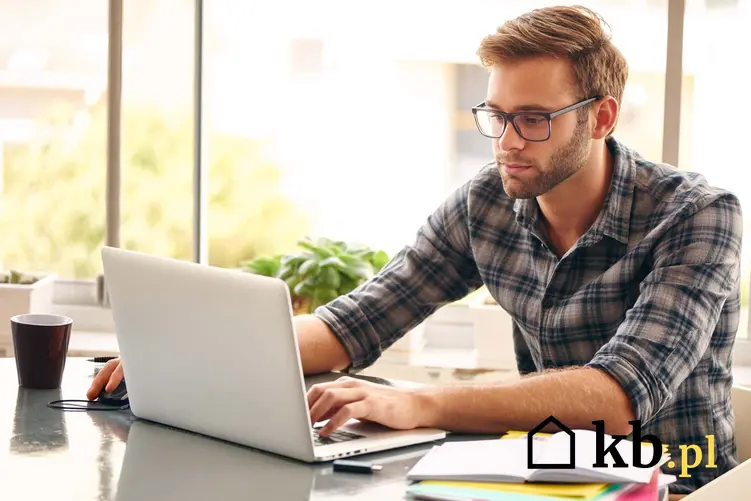 Mężczyzna w okularach siedzi przed laptopem, jak starać się o dofinansowanie do okularów używanych w pracy