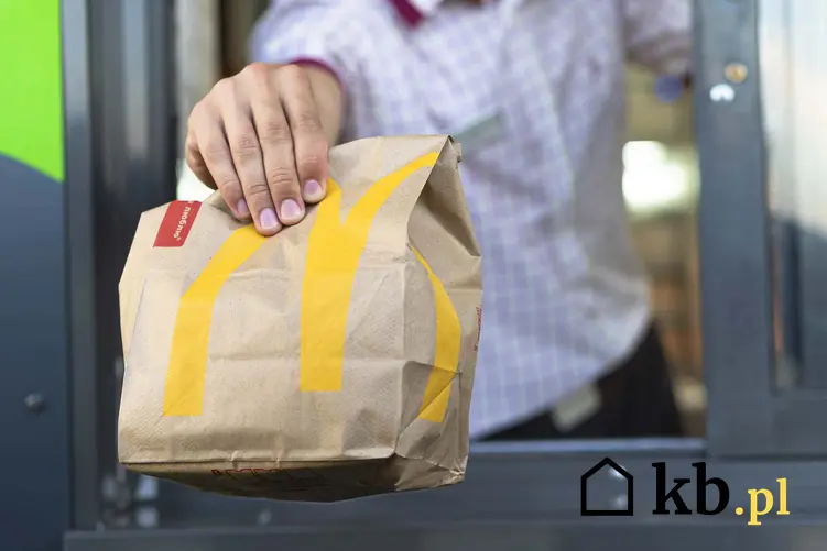 Pracownik McDonalds obsługuje klienta McDrive, pracownik McDonalds trzyma wyciagniętą rękę z posiłkiem w stronę klienta, ile kalorii mają sałatki w McDonalds
