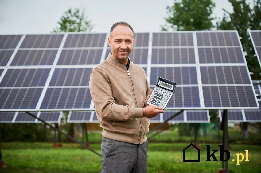 Dokładne wyliczenia i przemyślana strategia inwestycji w fotowoltaikę i magazyn energii są dziś kluczowe dla opłacalności. mężczyzna trzymający kalkulator przy panelach fotowoltaicznych