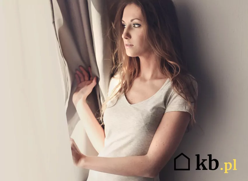 Pani Żaneta spogląda przez okno swojego mieszkania – życie w centrum miasta bez prywatności kobieta wygląda przez okno