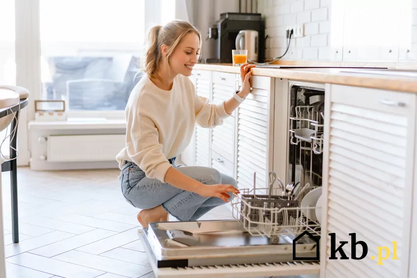 uśmiechnięta kobieta otwiera zmywarkę