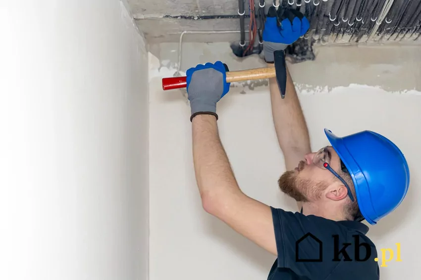 Ogrzewanie sufitowe to grzewczy system płaszczyznowy o niskiej temperaturze Mężczyzna montuje ogrzewanie sufitowe