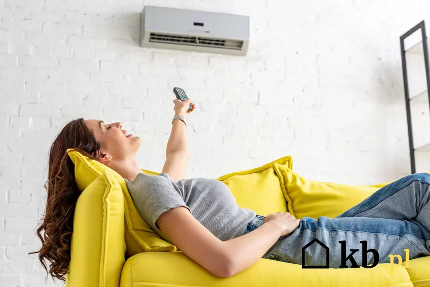 Choć używana klimatyzacja kusi atrakcyjną ceną, warto zastanowić się, co kryje się za tą oszczędnością. kobieta leżąca na kanapie przy klimatyzatorze