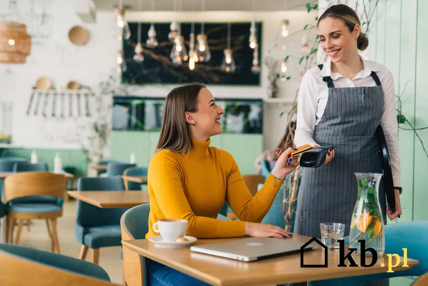 Kobieta płaci kartą w restauracji