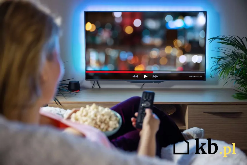 Opłata reprograficzna może zwiększyć ceny smart tv Kobieta oglądająca telewizję i jedząca popcorn