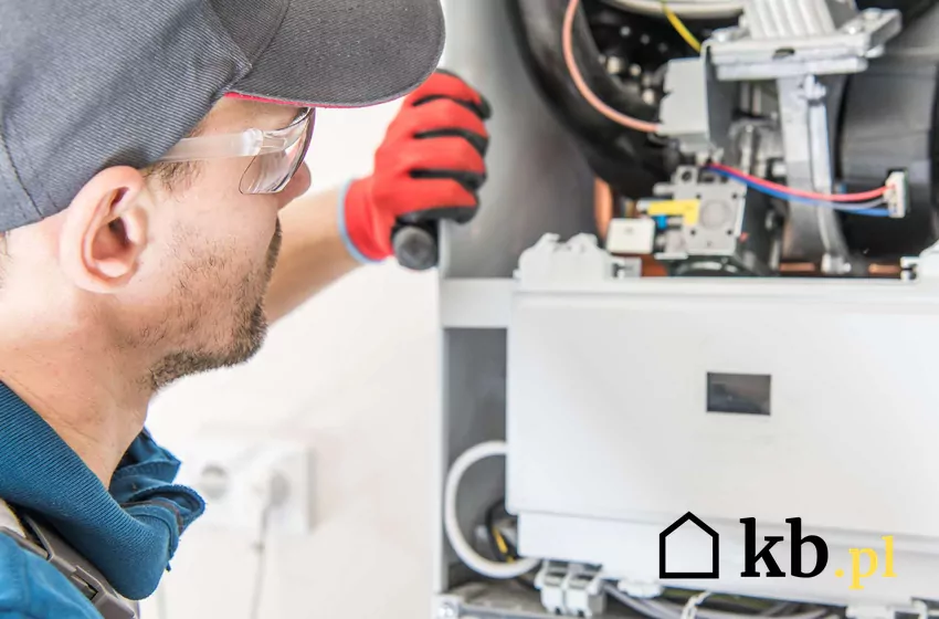 Instalator zaglądający do otwartego kotła kondensacyjnego