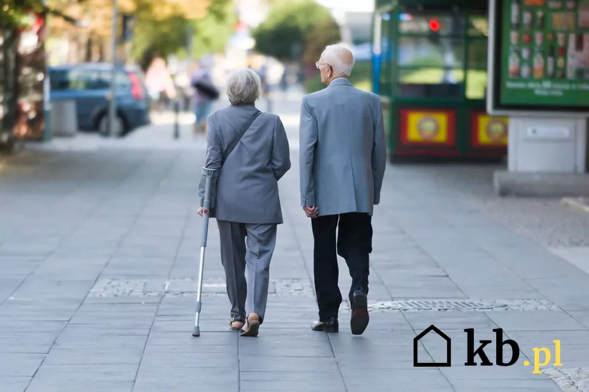 Dwie starsze osoby spacerują chodnikiem