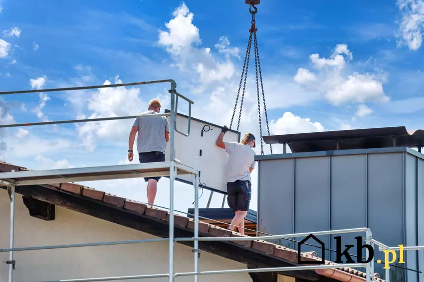 Dwóch mężczyzn demontuje panele fotowoltaiczne z dachu