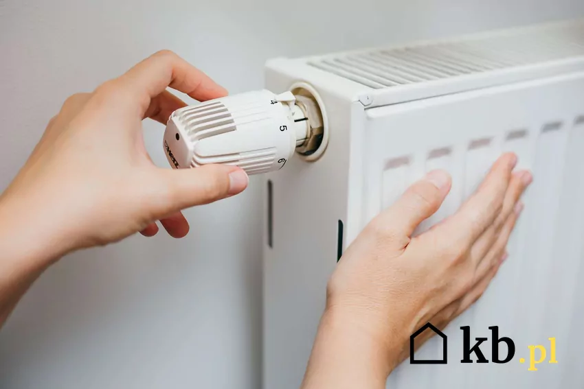 Dłonie regulujące pokrętło grzejnika