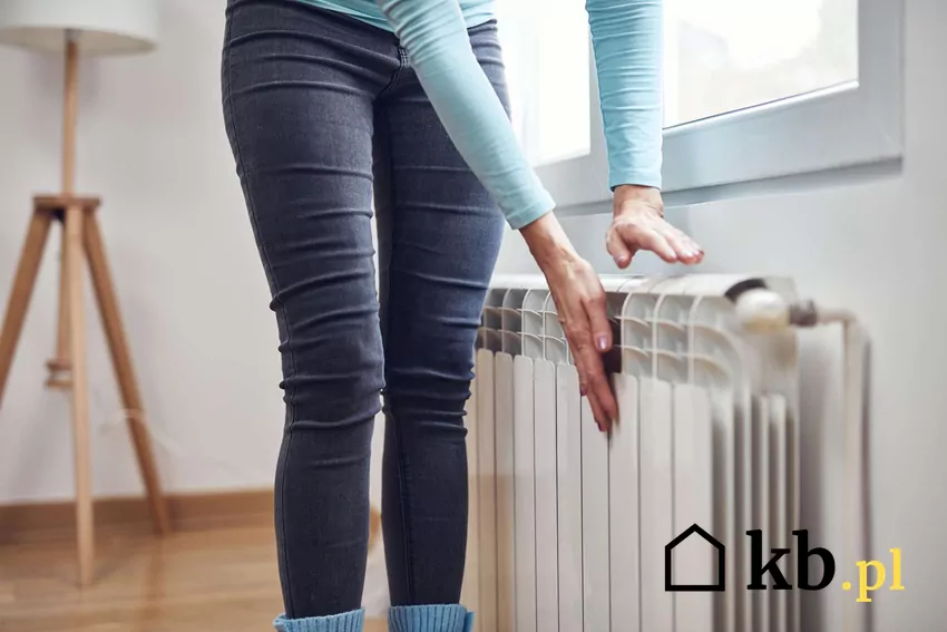 Kobieta trzyma dłonie na grzejniku