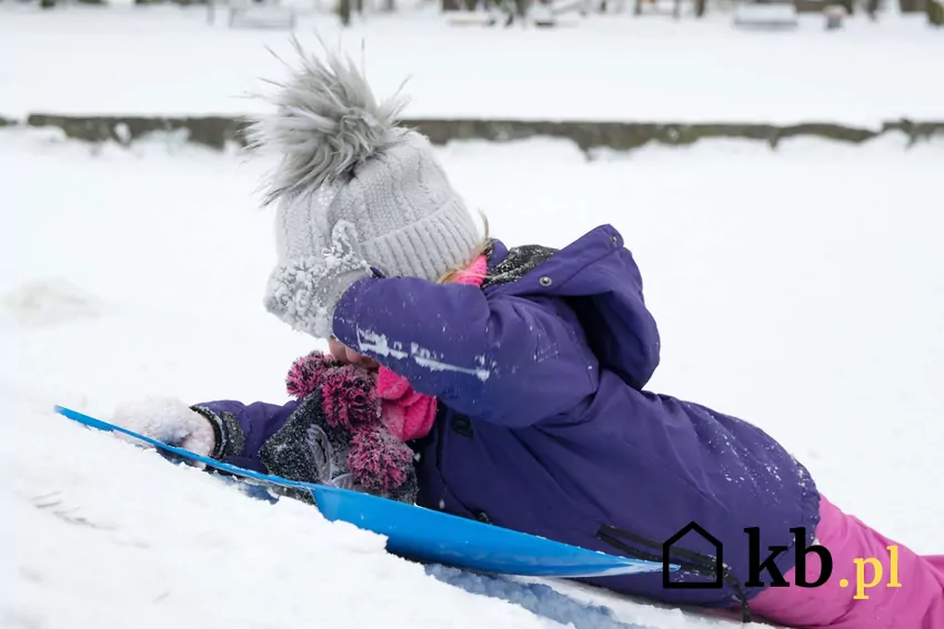 Wprowadzenie trzech tur ferii zimowych zaniepokoiło wielu rodziców Dziecko zjeżdża z górki na śniegu