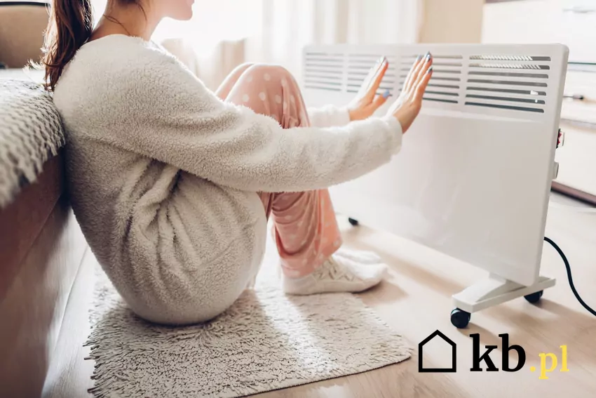 Ogrzewanie elektryczne może pochłonąć mnóstwo pieniędzy kobieta siedzi przy grzejniku elektrycznym