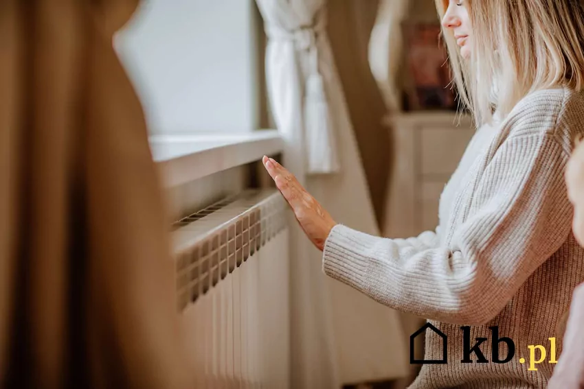 Młoda kobieta trzyma rękę na grzejniku