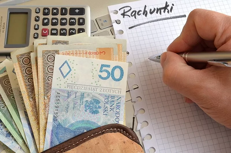 Faktury spółdzielni obejmują koszty związane z utrzymaniem nieruchomości, a członkowie mają prawo kwestionować nieprawidłowo naliczone opłaty. pieniądze leżące przy kalkulatorze i kartce z napisem "rachunki"