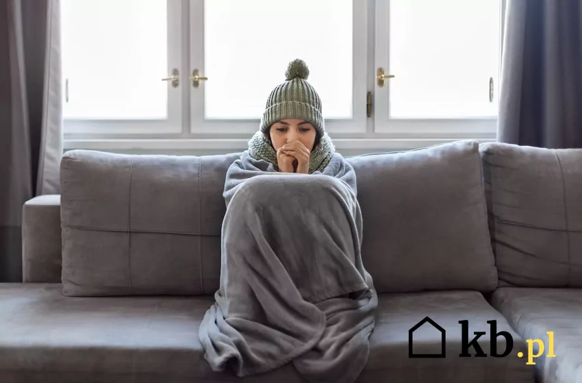 kobieta w czapce otula się kocem