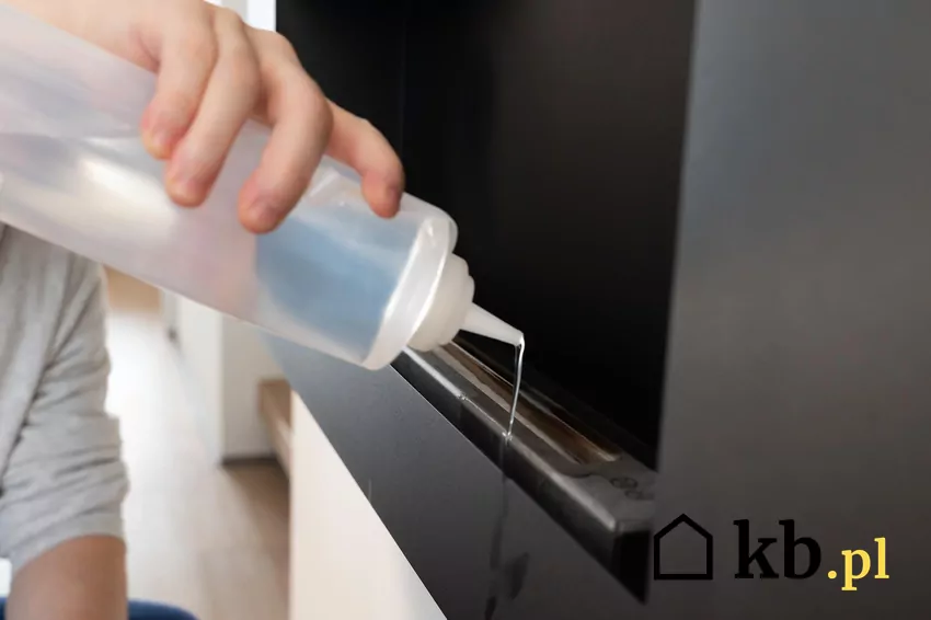 Mężczyzna dolewa etanol do biokominka