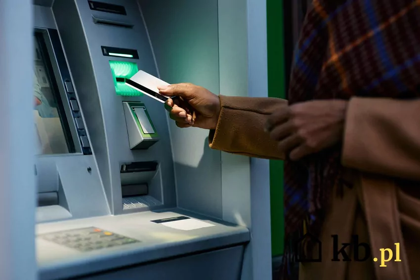 Mężczyzna wkłada kartę do bankomatu