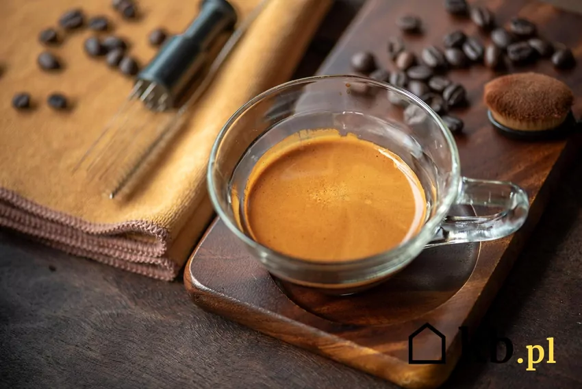 Filiżanka zaparzonej czarnej kawy, obok ziarna kawy