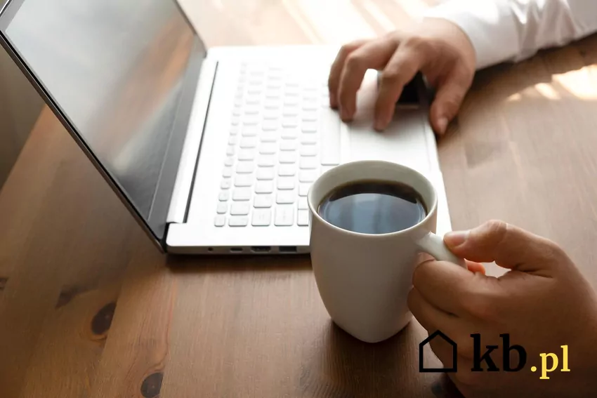 Pracowanie przy laptopie, obok ubek z czarną kawą