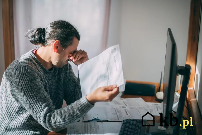 Załamany mężczyzna z rachunkami przy biurku