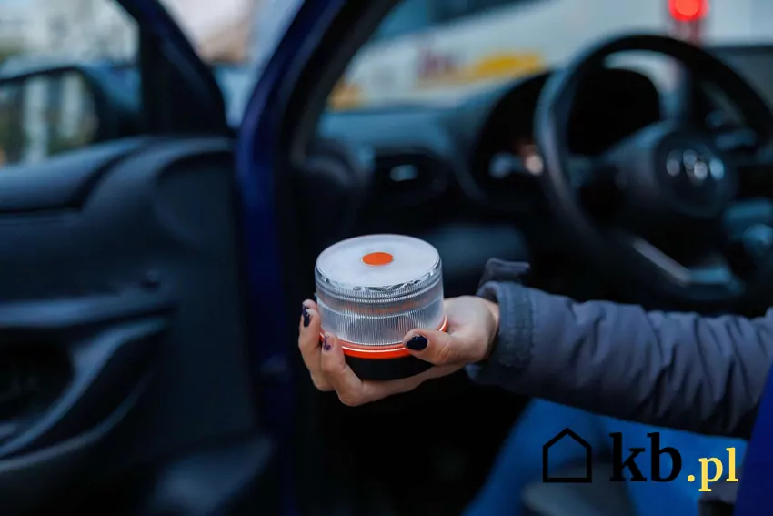 Kierowca samochodu wyciąga dłoń z lampą V-16