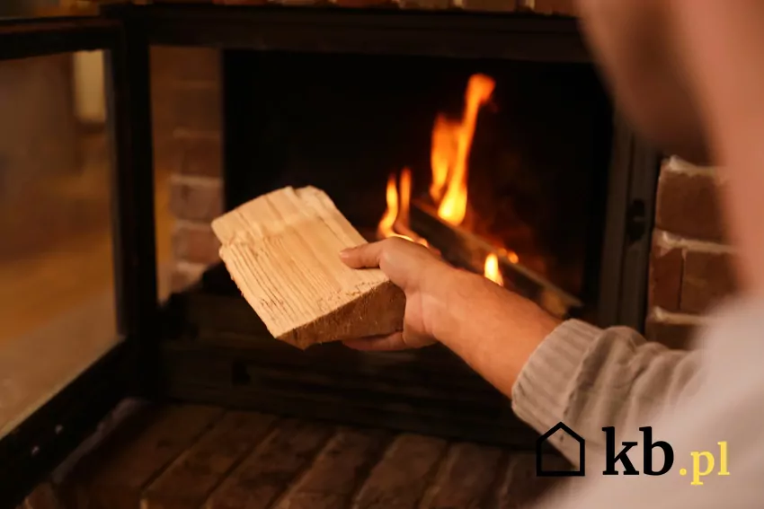 mężczyzna dokłada drewno do kominka