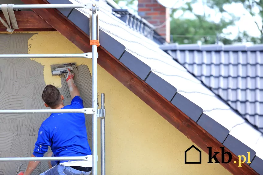 Tynkarze na rysztowaniu w trakcie nakładania tynku na ścianę budynku