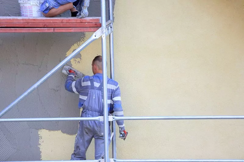 robotnicy podczas tynkowania elewacji