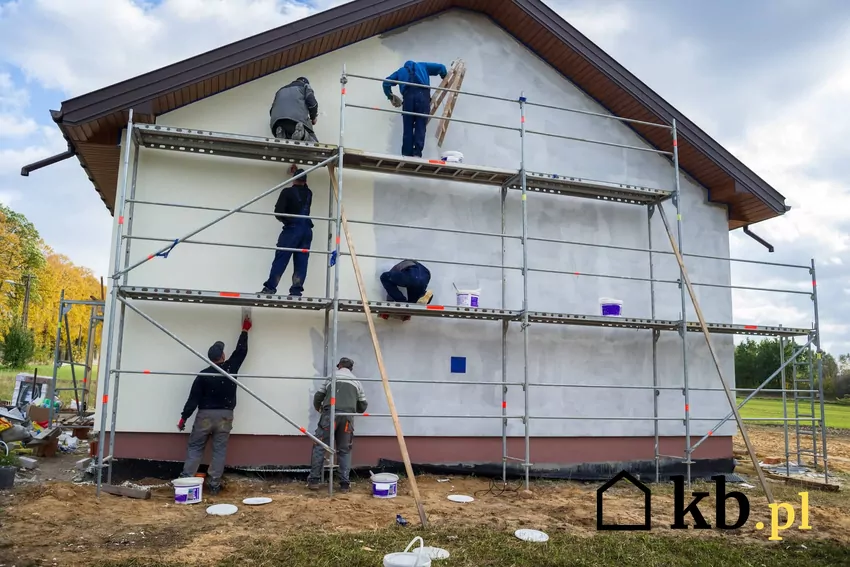 pracownicy tynkują ścianę domu
