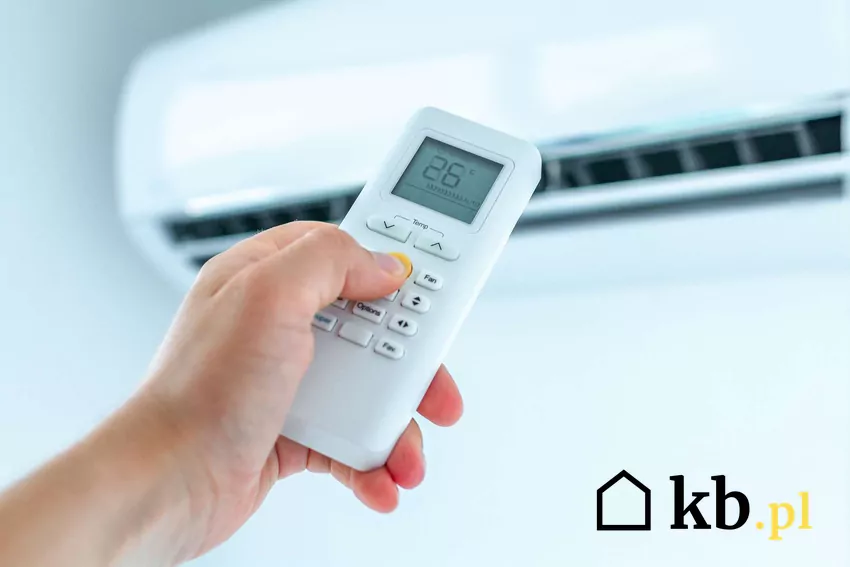 Ogrzewanie hybrydowe może przełożyć się na realne oszczędności Dłoń z pilotem wyciągnięta w stronę klimatyzatora
