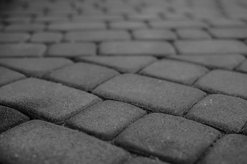 Prawidłowo wykonana podbudowa, geowłóknina i skuteczne odprowadzanie wody to klucz do trwałej i stabilnej nawierzchni z kostki brukowej. szara kostka brukowa