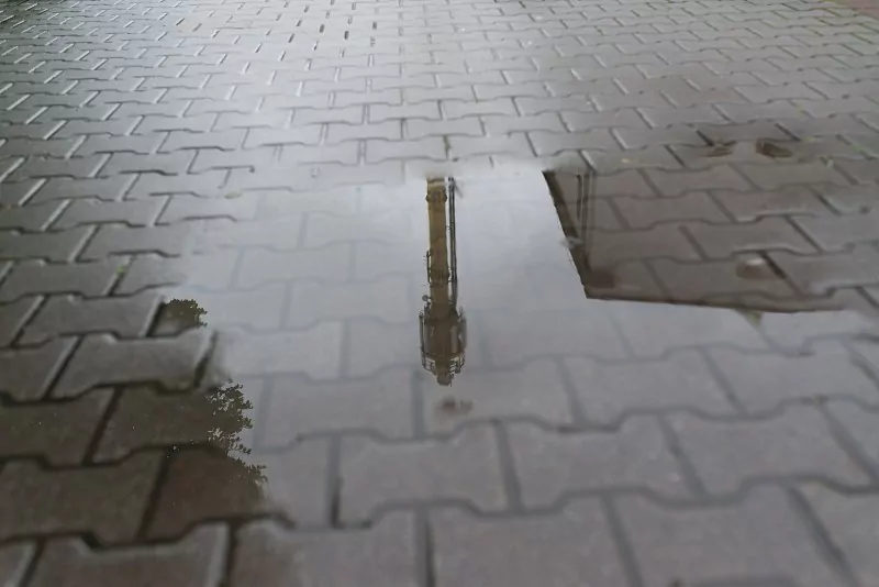 Kałuże utrzymujące się na nawierzchni mogą świadczyć o problemach z podbudową, spadkiem terenu lub odwodnieniem kostki brukowej. mokra kostka brukowa