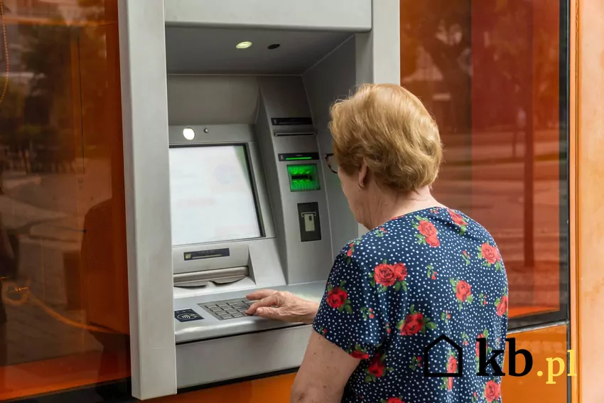 kobieta wypłaca pieniądze z bankomatu