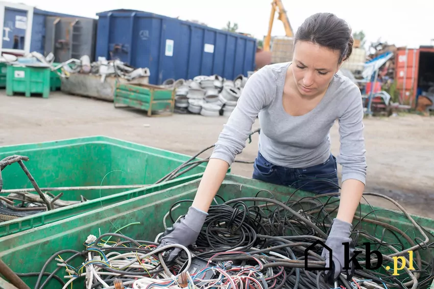 kobieta przebiera kable na złomowisku