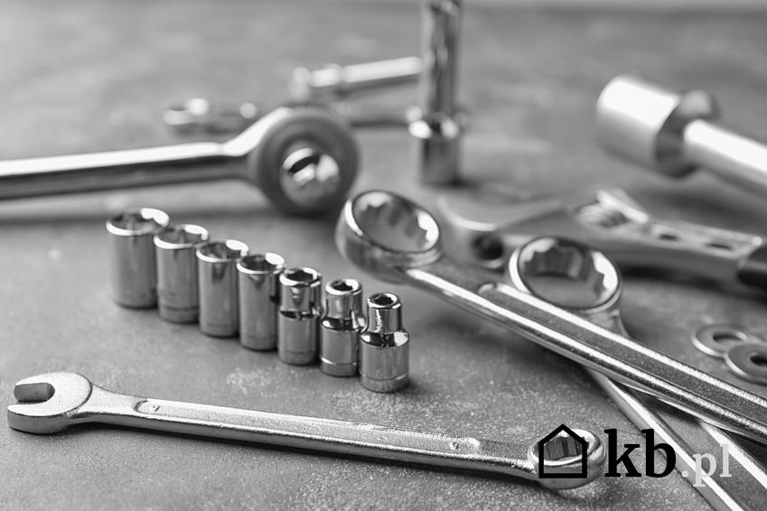 Różnego rodzaju klucze narzędziowe na stole, a także komplet kluczy nasadowych yato