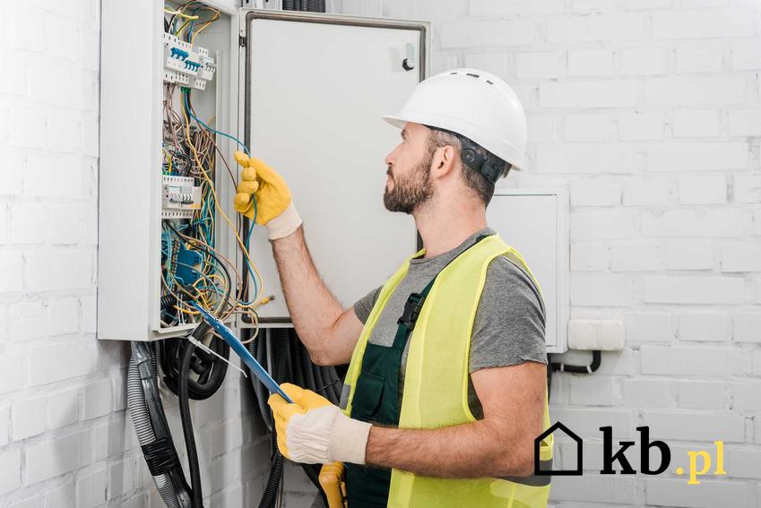 Mężczyzna naprawiający instalację elektryczną w domu jednorodzinnym, a także informacje, gdzie dzwonić, kiedy braknie prądu