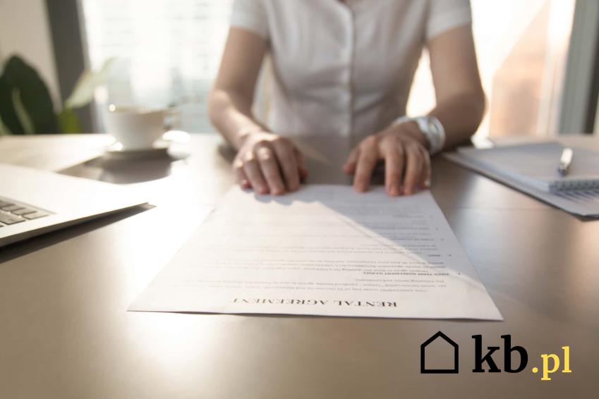 Kobieta za biurkiem z dokumentami, wypowiedzenie umowy przez właściciela lokalu lub mieszkania, wzór wypowiedzenia umowy najmu