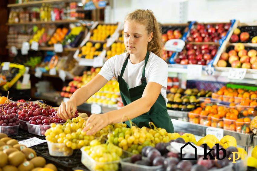 Dziewczyna układająca owoce w sklepie spożywczym, w jakim wymiarze godzin może pracować osoba niepełnoletnia, wysokość składek na ubezpieczenia społeczne młodocianych pracowników