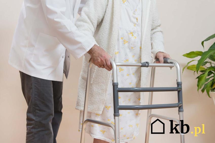 Starsza osoba przy balkoniku idąca z pomocą pielęgniarza, a także podpowiedzi, jak nie płacić za dom pomocy społecznej