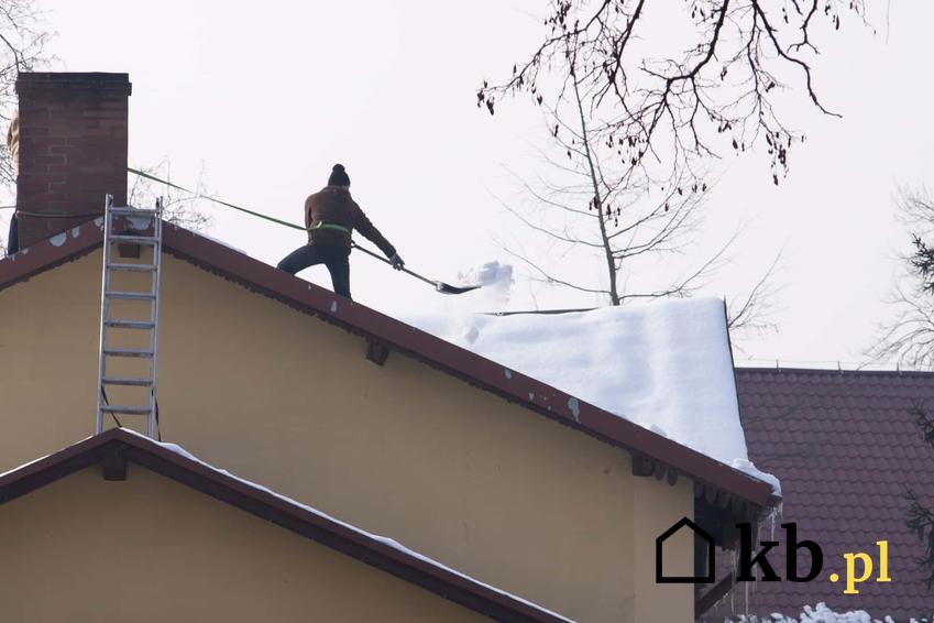 Mężczyzna podczas odśnieżania dachu, a także odśnieżanie dachów krok po kroku, najlepsze sposoby na usuwanie śniegu z dachu
